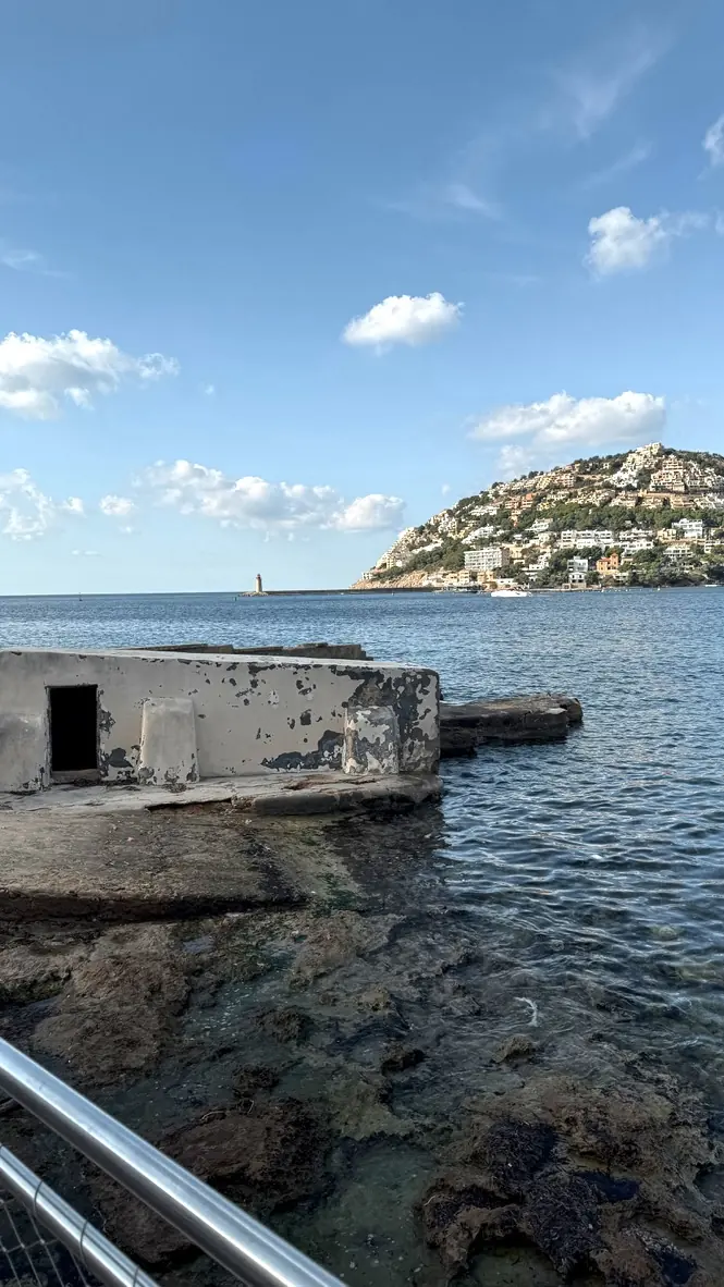 Felsküste an der Südwestküste Mallorcas mit Blick auf Leuchtturm und Hügelvillen