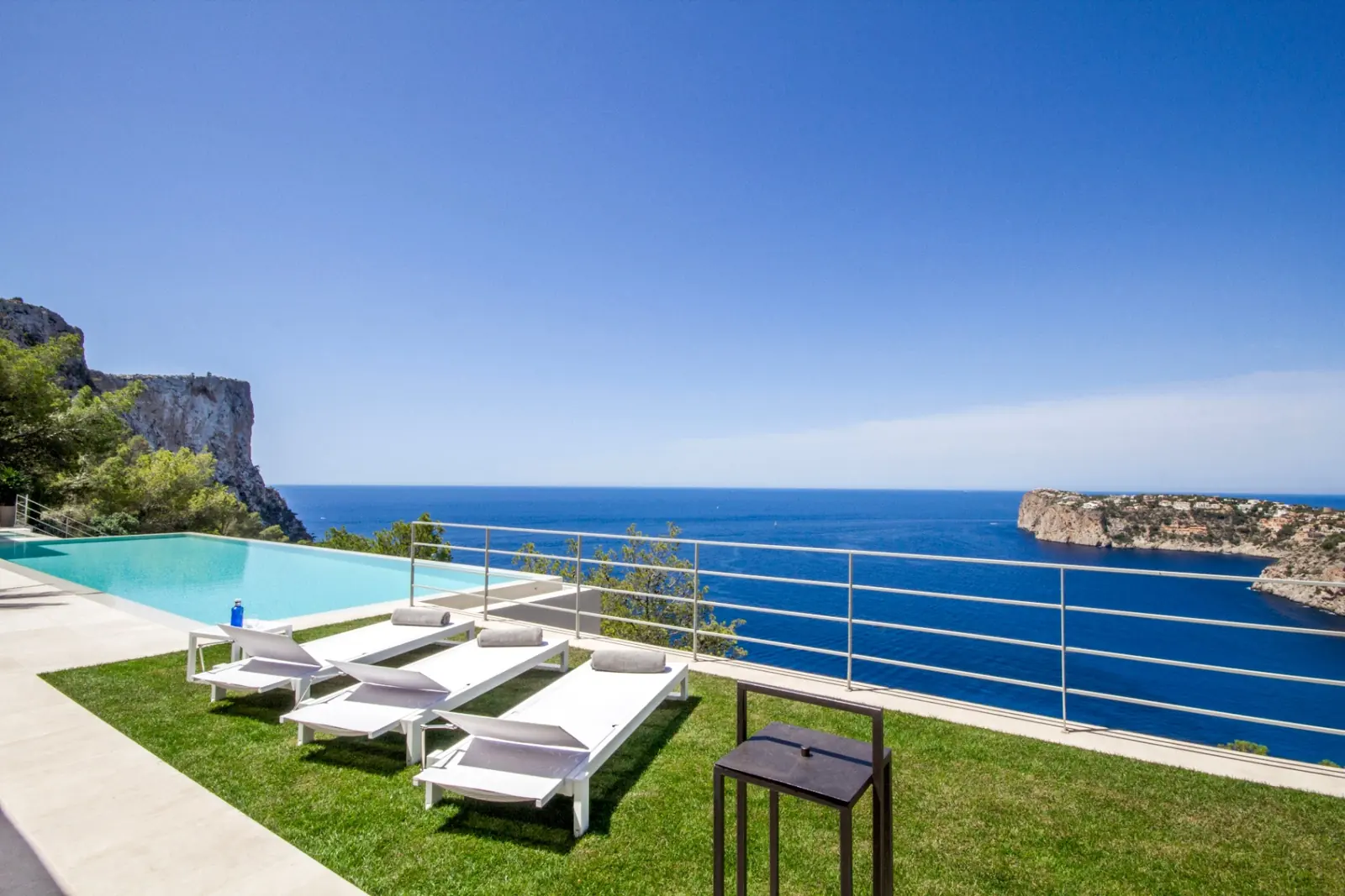 Infinity-Pool mit Meerblick und weißen Sonnenliegen über der Felsküste von Andratx