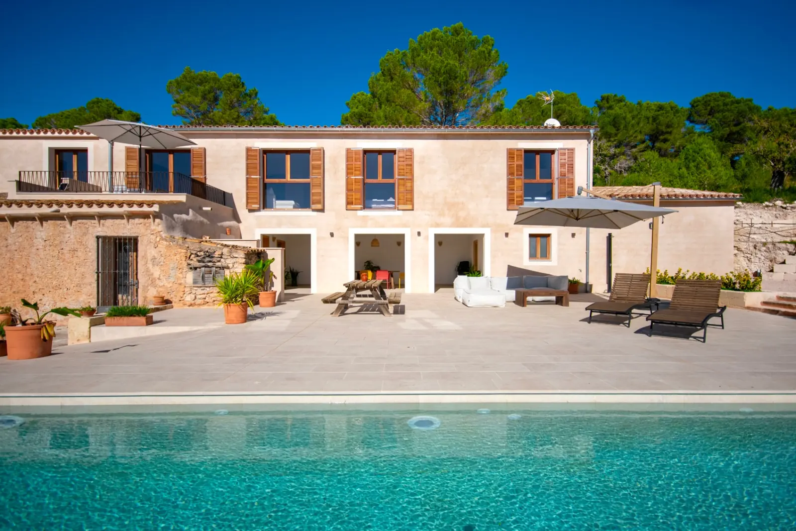 Sandstein-Finca auf Mallorca mit großem Pool und Sonnenschirmen